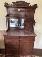 Full view of antique Victorian Eastlake buffet showing marble top, mirror, drawers, and door with carved decoration.