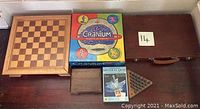 Wooden chess and backgammon board closed on top of wooden storage chest with Cranium and Mineral Quiz board games and a set of wooden pegs arranged around them.