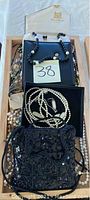 Photo displaying two black evening bags, one in a box along with pearl necklaces and various beaded costume jewelry.