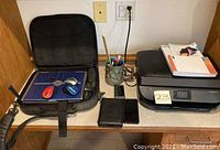HP OfficeJet 5255 printer, two small black electronic devices, ceramic mug with pens, and Dell laptop case with wireless mice on desk