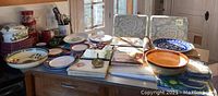 Various ceramic kitchenware pieces arranged on a table including plates, bowls and some cookbooks.