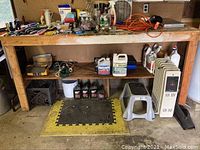Lower shelf with fluids, step stool and heater under workbench