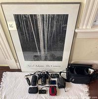 Framed Ansel Adams print leaning against wall with cameras and accessories laid out