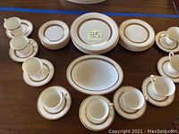Full top view of arranged set showing cups on saucers, bread plates, salad plates, dinner plates, and a large serving bowl