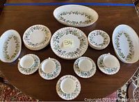 Overview of the china set including cups, saucers, plates, and serving bowls on a wooden table.