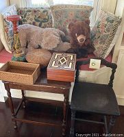 Overview of lot items including two stuffed animals, four floral throw pillows, wooden end table, child's chair, candle stand, and three decorative boxes on a bench with pink polka dot cushion and floral back pillows.