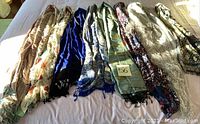 Photo showing six different scarves laid out on a surface, displaying their colors and patterns.