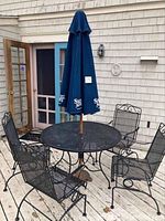 Full assembled patio set on wooden deck including round table, four chairs, umbrella