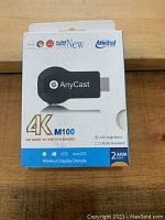 Front of the retail box showing AnyCast branding and 4K M100 model with feature highlights such as 2.4G single band, 2.4/5G dual band, iOS and macOS compatibility.