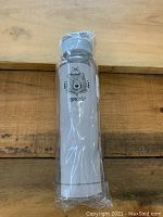 Front view of the BRQ'S water bottle in sealed plastic wrapping on wooden surface.