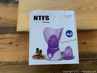 Box front showing NTFS Beauty facial steamer system with moisturing steamer label and image of purple device.