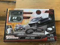 Box front showing Fast & Furious branding and two cars (Dodge Charger and police car) in clear window with racetrack illustration.
