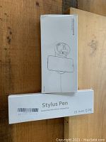 Photo of boxed iPhone/iWatch wireless charging pad and boxed stylus pen stacked on top of each other