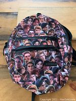 Front view of backpack showing character collage print and two zippered pockets