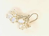 Pair of three-stone dangle earrings with translucent moonstones and silver hooks shown front side.