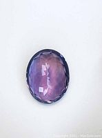 Top view of faceted deep purple amethyst stone showing clarity and oval shape.