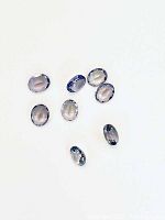 Eight oval tanzanite gemstones displayed on a white background.