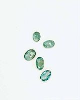 Five oval cabochon emerald gemstones on white background