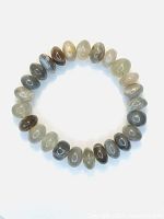Full circular bracelet made of rounded moonstone beads displaying various shades of gray, beige, and white with cat's eye flash.