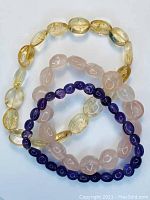 Set of three natural gemstone bracelets: citrine, rose quartz and amethyst on elastic cords