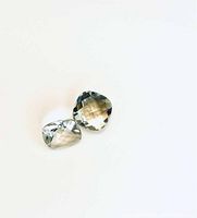 Two cushion checker cut green amethyst gemstones laid flat on white background, showing clarity and facets.