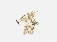 Top view of three pairs sterling silver earrings: four leaf clovers, dragons/serpents, scissors