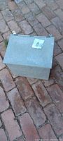 Closed view of rectangular metal box with lid and auction lot tag 403