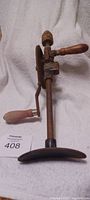 Front view of antique shoulder hand drill press with visible wooden handles and gears