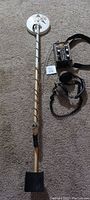 Full view of Fisher metal detector with control box, adjustable shaft, sensor coil, and attached headphones.