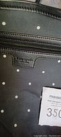 Close-up of Kate Spade leather logo label inside black polka dot tote bag
