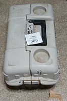 Closed white plastic fishing tackle box with black handle and two circular moldings on top surface.