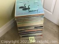 Stack of approximately 120 vintage LP and EP vinyl records piled on floor showing spines and covers, indicating a large mixed collection.