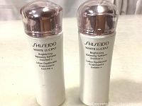 Front view of two white cylindrical bottles with rose-gold caps showing product name and branding.