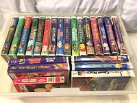 Photo showing assortment of 22 vintage Disney VHS tapes with spine titles visible in hard plastic case
