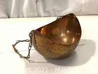Side view of the hammered copper Persian kashkul beggars bowl showing engraved floral motifs and brass chain attached.