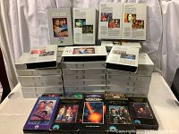 Stacked white VHS binder cases of original Star Trek TV series episodes with colorful movie VHS tapes in front.