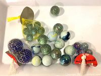 Full view of marbles collection including some in mesh bags and loose marbles spread on a white surface.