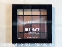 Front view of NYX Ultimate Eye Shadow Palette in black plastic case with 16 warm neutral eyeshadow shades visible through clear lid.