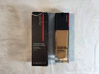 Photo of Shiseido Synchro Skin Radiant Lifting Foundation bottle next to box, showing full bottle and packaging.