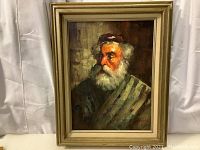 Full view of the framed oil painting showing the old man with white hair and beard, wearing a cap and cloak.