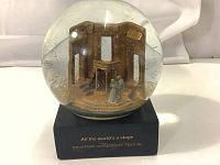 Glass globe showing the miniature Romeo and Juliet figures inside a detailed stage setting with gold glitter, mounted on a black base with festival branding