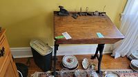 Image showing wooden box style desk with cast iron base and several office items on and below the desk including plates, stapler, and shredder at its side
