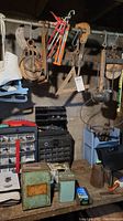 Wide view of lot contents on workbench and hanging hand saws, scale, and ice skates