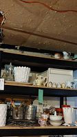 Photo showing various kitchenware including jars, cups, metal buckets, and cooling racks on shelves.