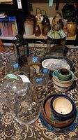 Lot showing various glassware including vases, cloches, stoneware crocks, lanterns, and planters displayed on patterned rug