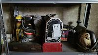 Overview of the shelf showing Yuasa battery charger in the original box, Craftsman router, red toolbox, metal lunch box, wooden box, and other tools
