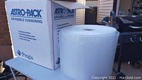 Photo showing large box labeled Astro-Pack Air-Bubble Cushioning with a large bubble wrap roll on top