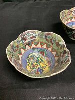 Top view of one hand painted flower-shaped bowl showing detailed bird and floral design with scalloped edges.