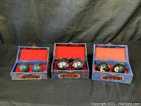 Three sets of Baoding balls in open decorative fabric-covered boxes with red velvet lining