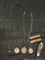 Photo showing all 4 necklaces, 2 wooden key sculptures, and pocket cutter arranged on black cloth background.